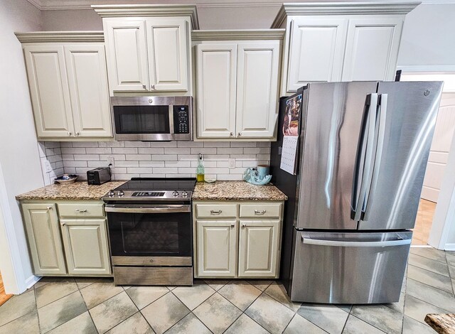 300 Woodson Dr, Tullahoma, TN 37388 - kitchen featuring appliances with stainless steel finishes, tasteful backsplash, light stone counters, crown molding, and light tile patterned floors