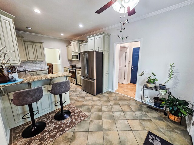 300 Woodson Dr, Tullahoma, TN 37388 - kitchen featuring appliances with stainless steel finishes, light stone countertops, decorative backsplash, a peninsula, and a breakfast bar
