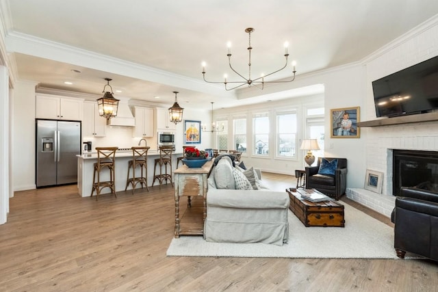 611 Lake Reserve Cv, Hermitage, TN 37076 - living room with a chandelier, crown molding, light wood finished floors, and a brick fireplace
