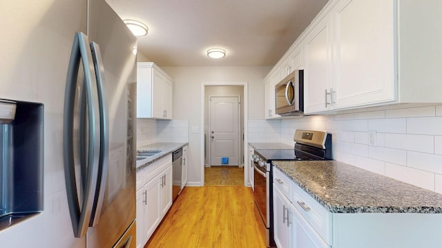 1807 Mosley Ferry Rd, Chapmansboro, TN 37035 - kitchen with stainless steel appliances, white cabinetry, decorative backsplash, and dark stone countertops