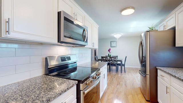 1807 Mosley Ferry Rd, Chapmansboro, TN 37035 - kitchen with stainless steel appliances, white cabinets, decorative backsplash, light wood-style flooring, and stone counters