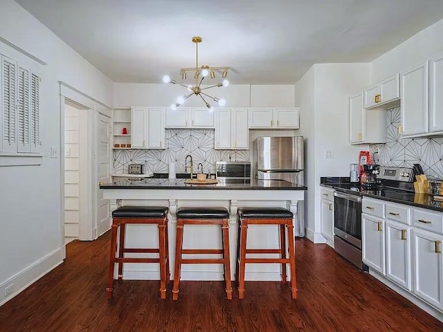 816 Charles Pl, Memphis, TN 38112 - kitchen featuring appliances with stainless steel finishes, a chandelier, dark countertops, decorative backsplash, and a breakfast bar area