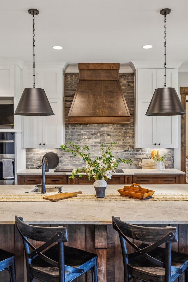 3166 Tanyard Hollow Rd, Culleoka, TN 38451 - kitchen with custom exhaust hood, a kitchen breakfast bar, white cabinets, tasteful backsplash, and pendant lighting
