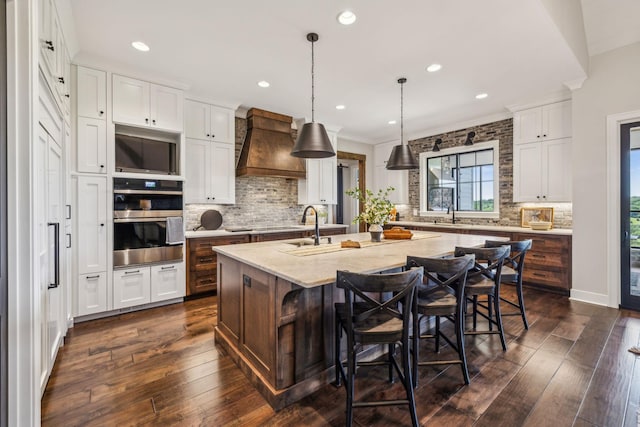 3166 Tanyard Hollow Rd, Culleoka, TN 38451 - kitchen featuring custom range hood, tasteful backsplash, stainless steel double oven, a kitchen island with sink, and white cabinets