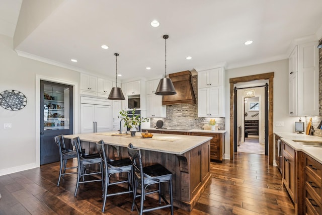 3166 Tanyard Hollow Rd, Culleoka, TN 38451 - kitchen with wall chimney range hood, decorative backsplash, a breakfast bar area, white cabinets, and dark wood-type flooring