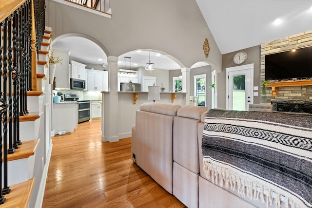6288 Blacksmith Dr, Pleasant View, TN 37146 - living room with light wood-style floors, arched walkways, high vaulted ceiling, stairway, and ornate columns