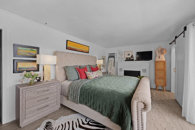 645 Attaway Ln, Bath Springs, TN 38311 - bedroom featuring a barn door, light wood finished floors, a brick fireplace, and baseboards