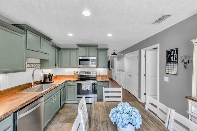 911 Keepsake Diamond Ln, Murfreesboro, TN 37128 - kitchen with green cabinetry, stainless steel appliances, a sink, wood counters, and recessed lighting