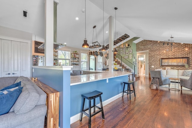 6416 Edsel Dr, Nashville, TN 37209 - kitchen with open floor plan, brick wall, a kitchen breakfast bar, dark wood finished floors, and hanging light fixtures