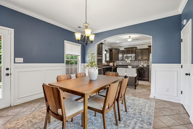 3296 Wiser Dr, Clarksville, TN 37042 - dining area with ornamental molding, arched walkways, light tile patterned flooring, wainscoting, and a chandelier