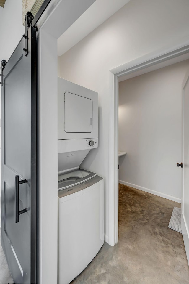 418 Boyd Mill Ave, Franklin, TN 37064 - laundry room featuring stacked washer and clothes dryer, a barn door, and baseboards