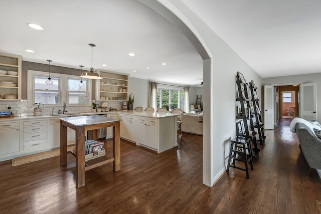 418 Boyd Mill Ave, Franklin, TN 37064 - kitchen featuring open shelves, arched walkways, a sink, a peninsula, and a kitchen bar