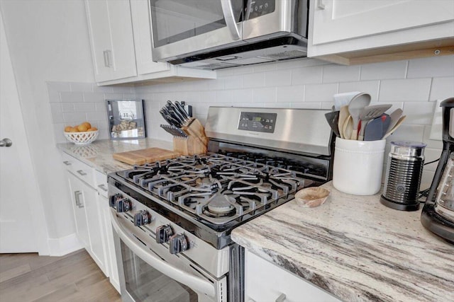 8792 Snowy Owl Rd, Ooltewah, TN 37363 - kitchen with appliances with stainless steel finishes, white cabinets, light stone counters, tasteful backsplash, and light wood-style floors