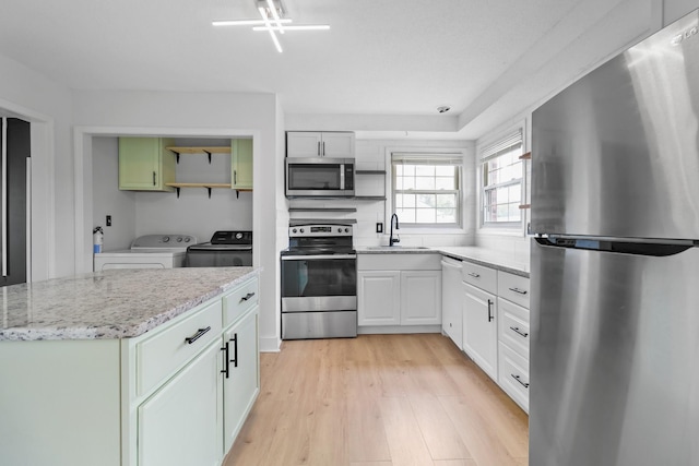 925 Tommy Oliver Rd, Clarksville, TN 37042 - kitchen with stainless steel appliances, separate washer and dryer, white cabinetry, light wood-style flooring, and light stone countertops