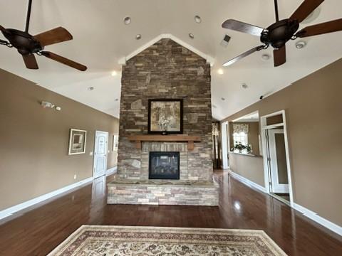 312 Mapleton Aly, Hermitage, TN 37076 - unfurnished living room featuring ceiling fan, a stone fireplace, wood finished floors, baseboards, and high vaulted ceiling