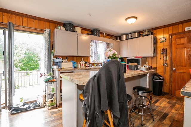 135 Old Union Church Rd, Holladay, TN 38341 - kitchen featuring light countertops, wooden walls, dark wood-style flooring, a breakfast bar area, and white cabinetry