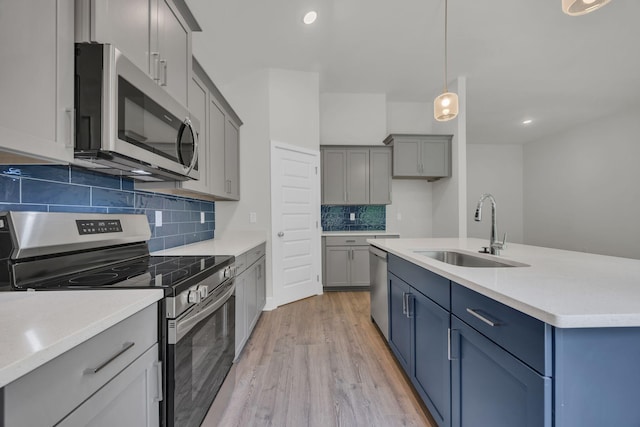 8545 Ari Ln, Chattanooga, TN 37421 - kitchen featuring appliances with stainless steel finishes, a sink, light wood-type flooring, decorative backsplash, and light countertops