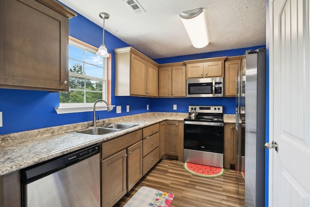 1217 Merritt Hill Trl, Smyrna, TN 37167 - kitchen featuring stainless steel appliances, a sink, wood finished floors, light countertops, and pendant lighting