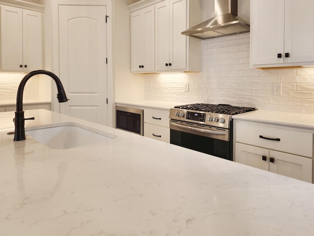7137 Frances St, Fairview, TN 37062 - kitchen featuring stainless steel range with gas stovetop, wall chimney range hood, a sink, black microwave, and decorative backsplash