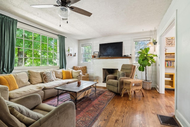 305 Andrews Ave, Hartsville, TN 37074 - living room featuring wood finished floors, a ceiling fan, a fireplace, a textured ceiling, and baseboards