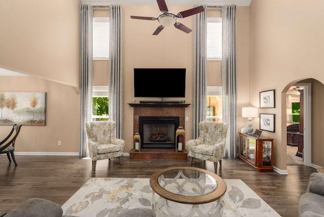 1056 Gilmore Hill Rd, Lebanon, TN 37087 - living room featuring a towering ceiling, a ceiling fan, arched walkways, a fireplace with raised hearth, and baseboards