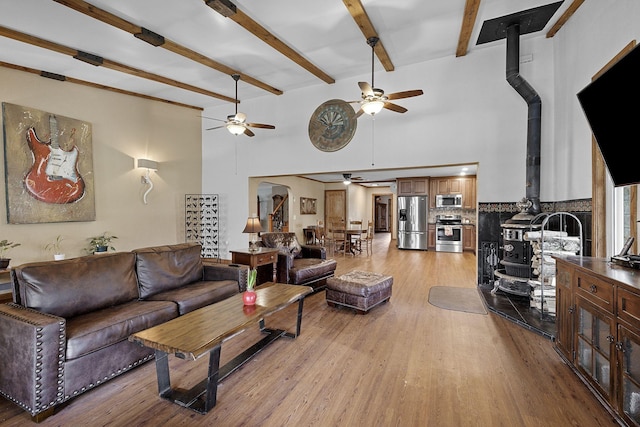 10669 S Windrow Rd, Rockvale, TN 37153 - living room featuring a ceiling fan, a wood stove, light wood-style flooring, beam ceiling, and a towering ceiling