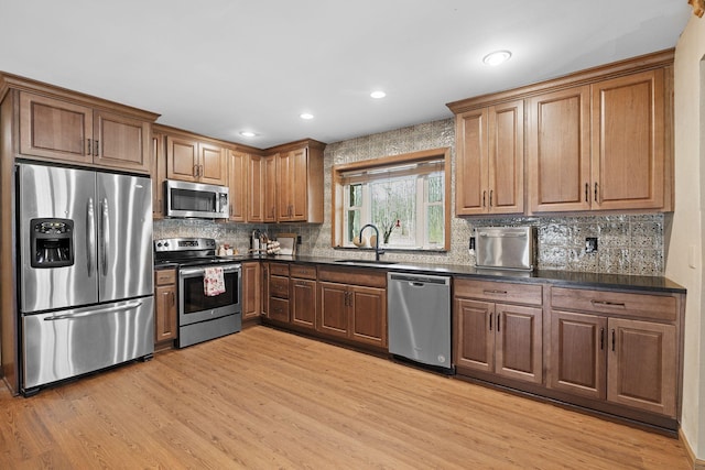 10669 S Windrow Rd, Rockvale, TN 37153 - kitchen with appliances with stainless steel finishes, a sink, dark countertops, light wood finished floors, and backsplash