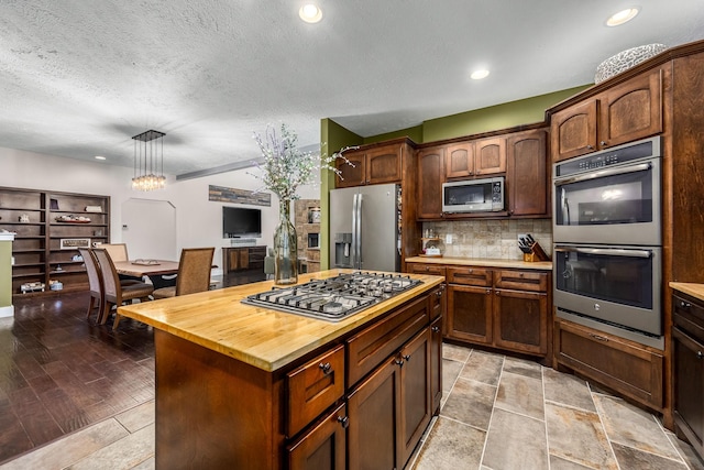 11 Walnut Creek Dr, Manchester, TN 37355 - kitchen with appliances with stainless steel finishes, decorative backsplash, hanging light fixtures, a textured ceiling, and a center island