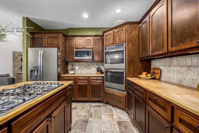 11 Walnut Creek Dr, Manchester, TN 37355 - kitchen with appliances with stainless steel finishes, butcher block counters, tasteful backsplash, light stone finish floors, and recessed lighting