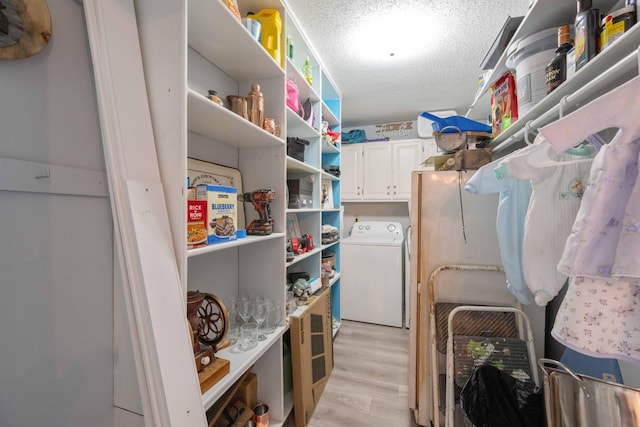 5935 Old Stage Rd, Huntingdon, TN 38344 - laundry area featuring washer / clothes dryer, cabinet space, light wood-style floors, and a textured ceiling
