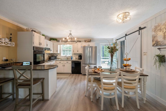 5935 Old Stage Rd, Huntingdon, TN 38344 - kitchen with black appliances, light wood finished floors, a textured ceiling, a barn door, and a chandelier