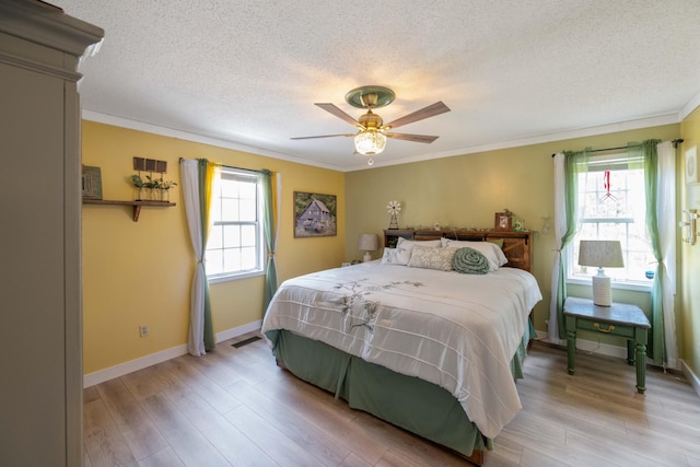 5935 Old Stage Rd, Huntingdon, TN 38344 - bedroom with multiple windows, a textured ceiling, light wood finished floors, ornamental molding, and baseboards