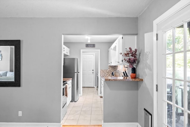 517 Ginkgo Dr, Clarksville, TN 37042 - kitchen with freestanding refrigerator, white cabinetry, light tile patterned flooring, a textured ceiling, and tasteful backsplash