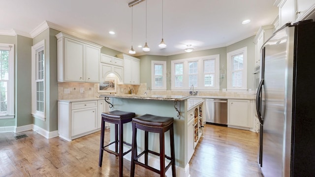 103 Doral Ln, Hendersonville, TN 37075 - kitchen with appliances with stainless steel finishes, ornamental molding, a breakfast bar, healthy amount of natural light, and white cabinetry