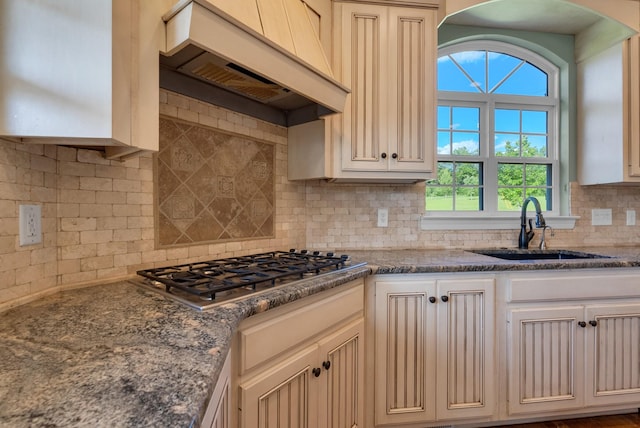 3840 SE Tater Peeler Rd, Lebanon, TN 37090 - kitchen featuring premium range hood, stainless steel gas stovetop, a sink, backsplash, and dark stone counters