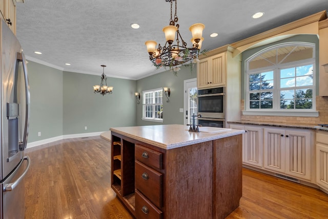 3840 SE Tater Peeler Rd, Lebanon, TN 37090 - kitchen featuring cream cabinets, a chandelier, stainless steel appliances, a center island, and wood finished floors