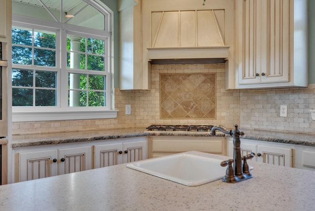 3840 SE Tater Peeler Rd, Lebanon, TN 37090 - kitchen featuring custom exhaust hood, tasteful backsplash, light stone counters, and stainless steel gas stovetop