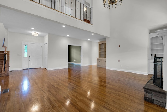 3840 SE Tater Peeler Rd, Lebanon, TN 37090 - unfurnished living room with built in shelves, wood finished floors, baseboards, a fireplace with raised hearth, and recessed lighting