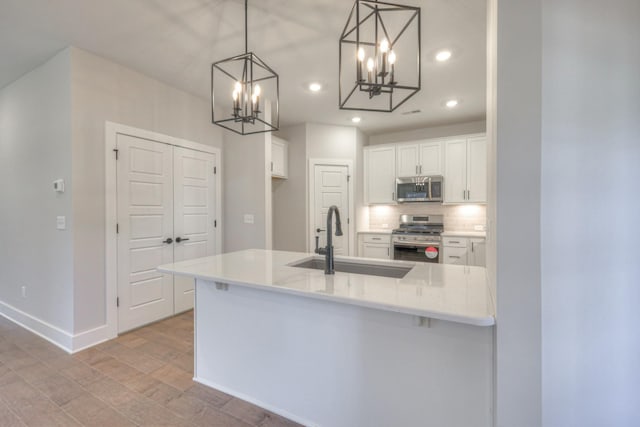 9067 Headwaters Dr Unit 141, Franklin, TN 37064 - kitchen featuring stainless steel appliances, a sink, a chandelier, white cabinetry, and backsplash