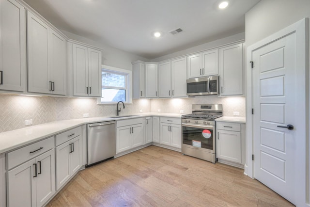 90883 Headwaters Dr Unit 143, Franklin, TN 37064 - kitchen with appliances with stainless steel finishes, a sink, backsplash, light wood-style floors, and light countertops