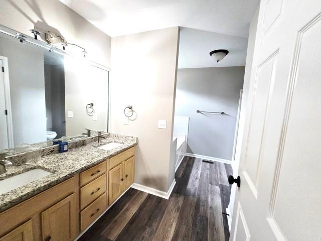 6356 Paddington Way, Antioch, TN 37013 - full bath featuring double vanity, wood finished floors, toilet, a bath, and baseboards