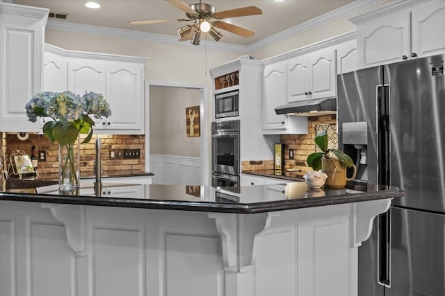 7244 Knottingham Dr, Fairview, TN 37062 - kitchen with stainless steel appliances, dark countertops, white cabinetry, a ceiling fan, and under cabinet range hood