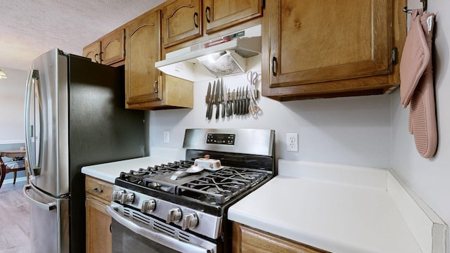 3507 Watts Ln, Murfreesboro, TN 37127 - kitchen with stainless steel appliances, under cabinet range hood, light countertops, brown cabinets, and a textured ceiling
