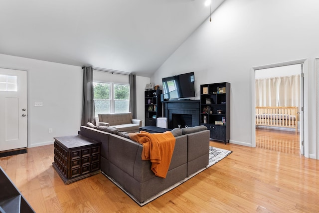 515 S Cedar Ln, Pulaski, TN 38478 - living area with light wood-type flooring, a brick fireplace, high vaulted ceiling, baseboards, and radiator heating unit