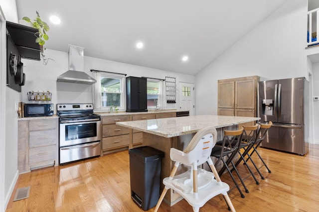 515 S Cedar Ln, Pulaski, TN 38478 - kitchen with appliances with stainless steel finishes, wall chimney range hood, a breakfast bar area, a kitchen island, and light wood-type flooring