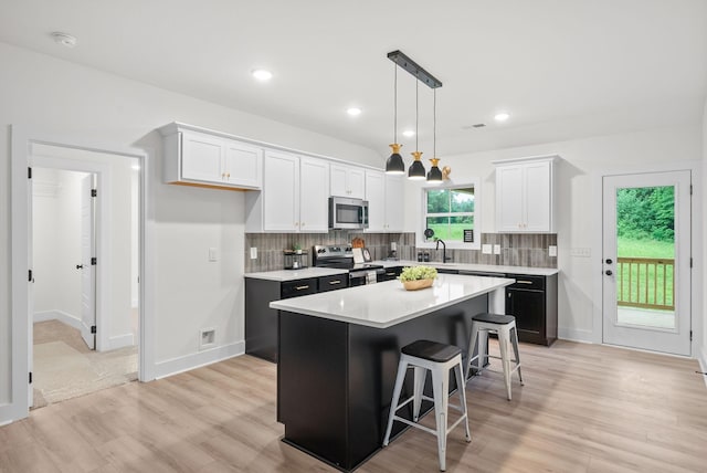 185 Dewberry Ct, Clarksville, TN 37042 - kitchen with stainless steel appliances, a center island, white cabinetry, light wood-style floors, and light countertops