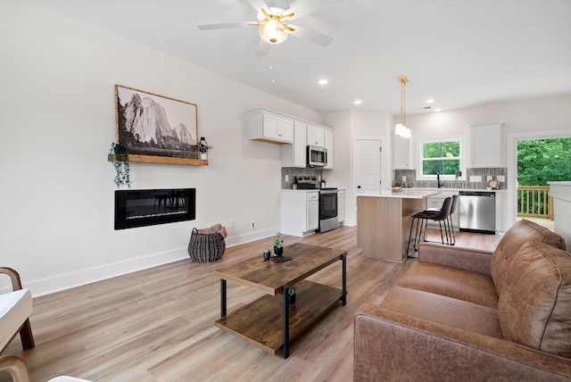 197 Dewberry Ct, Clarksville, TN 37042 - living area with light wood-type flooring, ceiling fan, a glass covered fireplace, recessed lighting, and baseboards