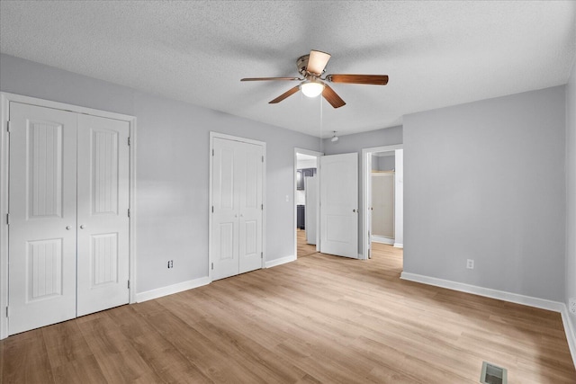 724 Shelly Ln, Rossville, GA 30741 - unfurnished bedroom with light wood-type flooring, multiple closets, a textured ceiling, and a ceiling fan