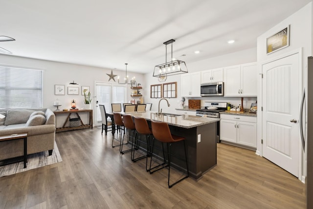 1006 Pepper Stone Dr, Lebanon, TN 37087 - kitchen featuring appliances with stainless steel finishes, a sink, a breakfast bar area, white cabinetry, and light stone counters