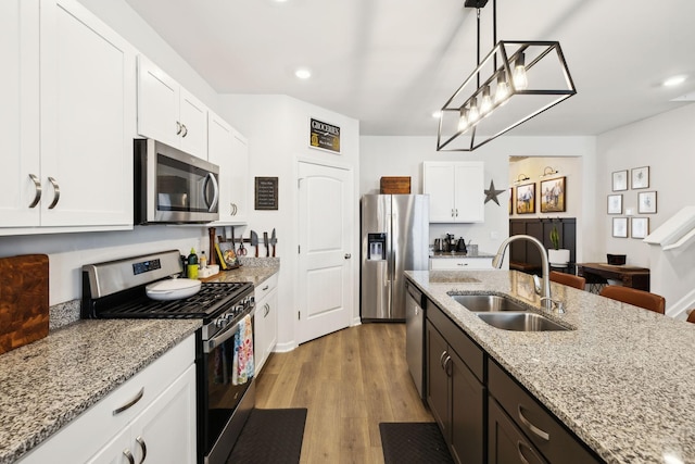 1006 Pepper Stone Dr, Lebanon, TN 37087 - kitchen featuring stainless steel appliances, a sink, white cabinetry, hanging light fixtures, and light wood-type flooring